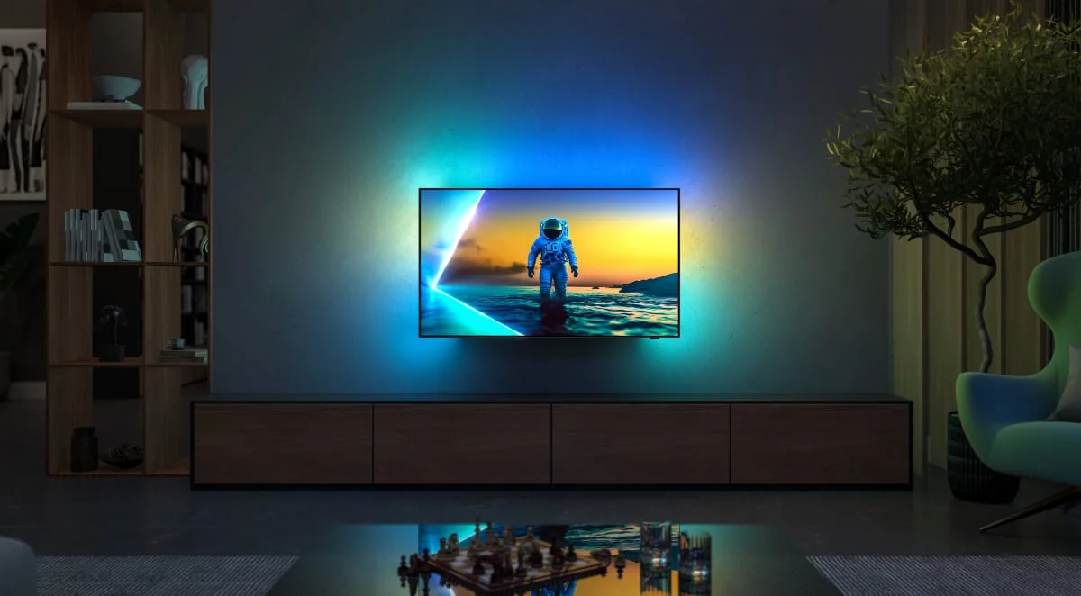 Na zdjęciu znajduje się Philips 810, telewizor OLED klasy premium z funkcją Ambilight, która dynamicznie dopasowuje kolory podświetlenia do obrazu na ekranie. Model oferuje szeroką gamę formatów HDR, żywe barwy oraz płynny ruch dzięki zaawansowanej technologii przetwarzania obrazu. Stylowy design i smukłe ramki sprawiają, że idealnie komponuje się w nowoczesnych wnętrzach.