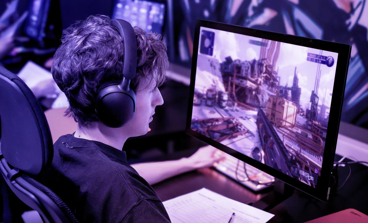 E-Sport-Spieler am OLED-Monitor: "Professioneller E-Sport-Spieler, der an einem OLED-Monitor spielt – ideale Bedingungen für das Spielen dank lebendiger Farben und tiefem Schwarz, unterstützt durch eine 3-jährige Garantie gegen Einbrennen des Panels. Die OLED-Technologie unterstützt lange Gaming-Sessions, ohne Angst vor dem Einbrennen des Bildschirms zu haben.